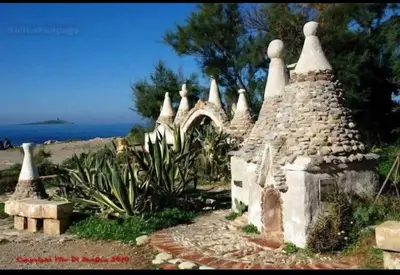 a small stone building with the ocean in the background at House victor in Palermo