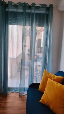 a living room with blue curtains and a blue couch at utveggio view apartment in Palermo