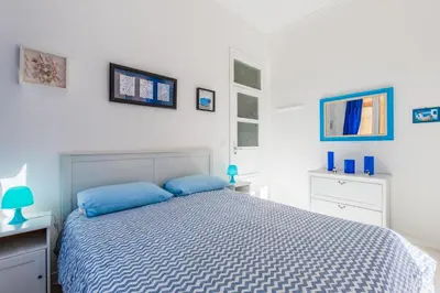 a white bedroom with a bed with blue pillows at Casa Soliva al Centro di Palermo in Palermo