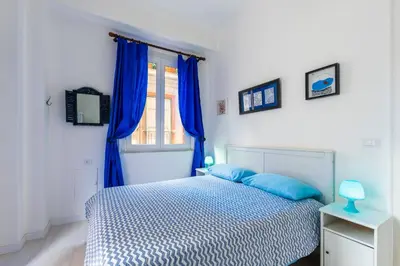 a bedroom with a bed and a window with blue curtains at Casa Soliva al Centro di Palermo in Palermo