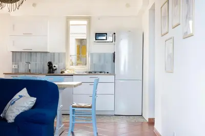 a kitchen with a blue chair and a white refrigerator at Arancina Abbronzata in Balestrate