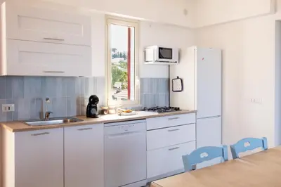 a kitchen with white cabinets and a white refrigerator at Arancina Abbronzata in Balestrate
