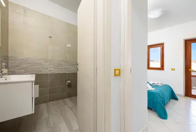 a bathroom with a sink and a bed in a room at Bilocale Piano Terra a 400 mt dal mare in San Vito lo Capo