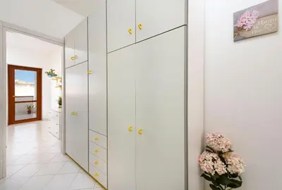 a hallway with white cabinets and a vase of flowers at Bilocale Piano Terra a 400 mt dal mare in San Vito lo Capo