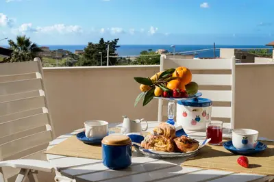 a table with a tray of breakfast food on a balcony at Gioia Guesthouse in Alcamo