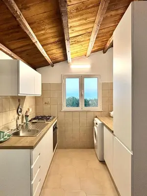 a kitchen with white cabinets and a sink and two windows at Casa Sulla Spiaggia Villa Eléftheria in Altavilla Milicia