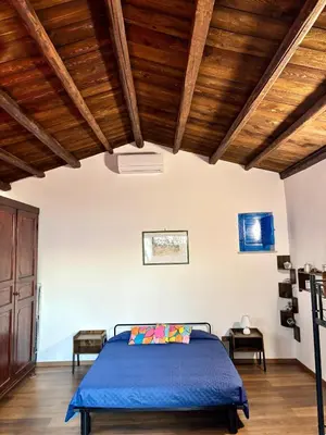 a bedroom with a blue bed and wooden ceilings at Casa Sulla Spiaggia Villa Eléftheria in Altavilla Milicia