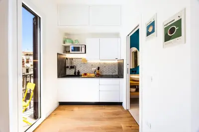 a kitchen with white cabinets and a wooden floor at Appartamenti Pellegrino Centro in Palermo