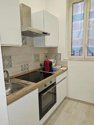 a kitchen with white cabinets and a sink and a window at Casa Amato appartamento alla zisa in Palermo