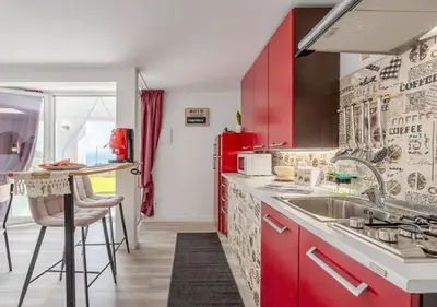 a red kitchen with a sink and a counter at Villa dei tramonti in Terrasini