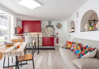 a living room with a couch and a kitchen with red cabinets at Villa dei tramonti in Terrasini