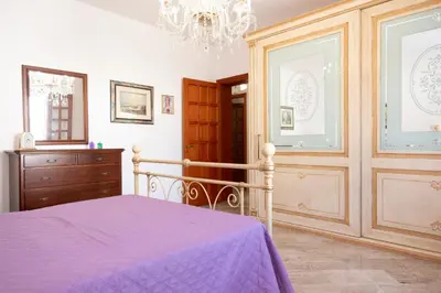 a bedroom with a purple bed and a chandelier at Casa Lucido di fronte la Tonnara in San Vito lo Capo