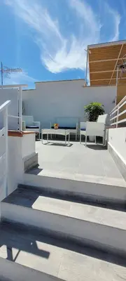 a patio with two benches and a white wall at Idea di Mare in Capaci