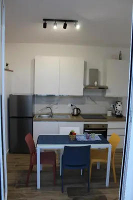 a kitchen with a table and chairs and a kitchen with white cabinets at Idea di Mare in Capaci