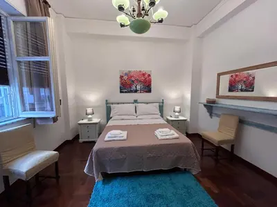 a bedroom with a bed with two chairs and a blue rug at Bellammari Holiday House in Palermo
