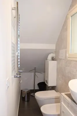 a white bathroom with a toilet and a sink at Duomo Suite - A Step from the Cathedral in Monreale