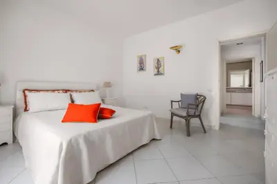 a white bedroom with a bed with two red pillows at Villa Angela By DomuSicily in Capaci