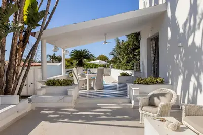 a white house with white furniture and palm trees at Villa Angela By DomuSicily in Capaci