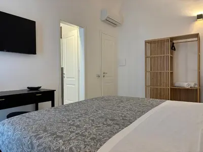 a bedroom with a bed and a desk and a television at Historic Palazzo - Apartments & Rooms with Private Bathroom in Palermo