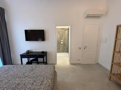 a bedroom with a bed and a desk and a television at Historic Palazzo - Apartments & Rooms with Private Bathroom in Palermo
