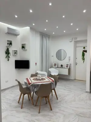 a white living room with a table and chairs at A Casa di Giro suite apartment in Palermo
