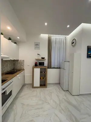 a kitchen with white cabinets and a marble floor at A Casa di Giro suite apartment in Palermo