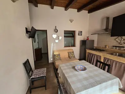 a living room with a table and a kitchen at Casa Vacanza Isola di Eufemio in Capaci