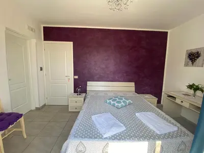 a bedroom with a bed with a purple wall at Le Ortensie Appartamento Grande in San Vito lo Capo