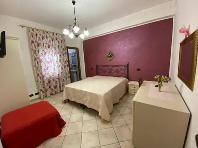 a bedroom with a bed and a red chair at Le Ortensie Appartamento Grande in San Vito lo Capo