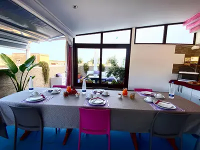 a dining room with a table and pink chairs at Le Ortensie Appartamento Grande in San Vito lo Capo
