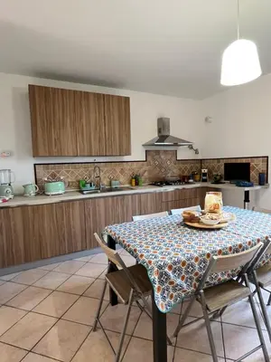 a dining room table with chairs and a kitchen at A Casa Da Mari' in Terrasini