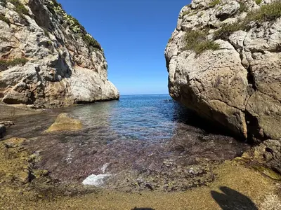 a large rock on a beach next to the ocean at AWA Kafara in Porticello