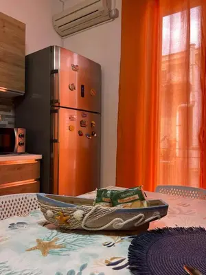 a kitchen with a stainless steel refrigerator and a table at La rosa dei venti in Isola delle Femmine
