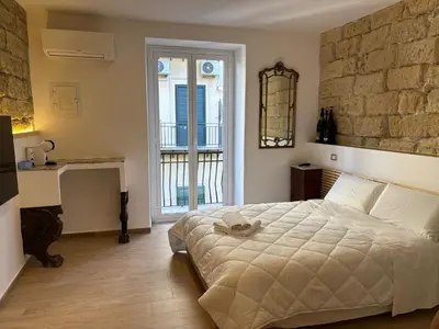 a bedroom with a large bed and a stone wall at Palermo Sunset in Palermo
