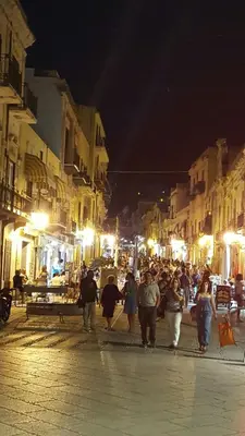 a group of people walking down a street at night at Casa vacanze Giusi in Castellammare del Golfo
