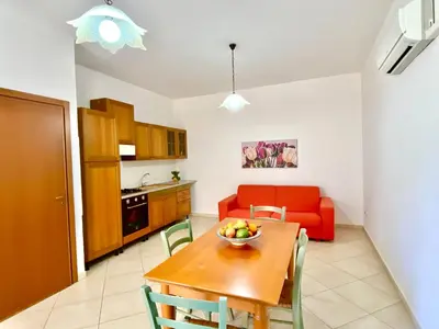 a living room with a red couch and a kitchen at Residence Piana, San Vito Lo Capo in San Vito lo Capo