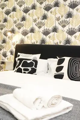 a bed with black and white pillows and a wallpaper at Da Vera Apartment in Palermo