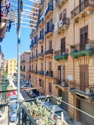 a building with balconies and cars on a street at Da Vera Apartment in Palermo