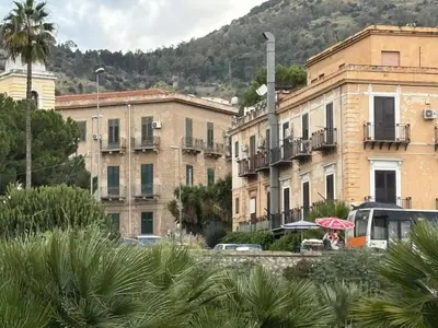 a woman sitting under an umbrella in front of buildings at La Casa di Alan in Palermo