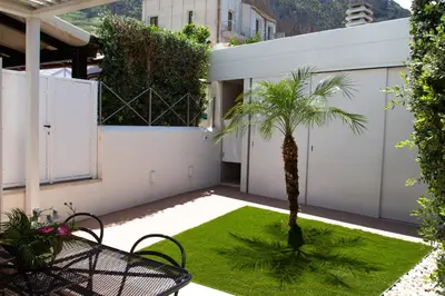 a small garden with a palm tree on a patio at Anemos Apartment - Villa Luna in Macari