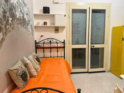 an orange bed in a room with sliding glass doors at Orange Lemon Business Palermo in Palermo