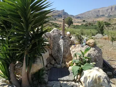 a shower in a rock with a palm tree at Casetta Rosina in Scopello