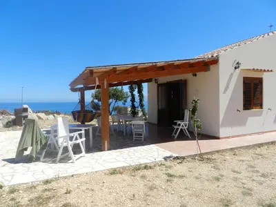 a patio of a house with a table and chairs at Casetta Rosina in Scopello
