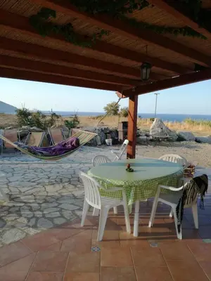 a patio with a table and chairs and a hammock at Casetta Rosina in Scopello