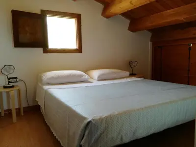 a bedroom with a large bed with a window at Casetta Rosina in Scopello