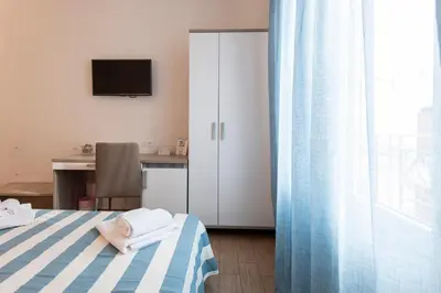 a bedroom with a bed and a desk with a television at La Nicchia in San Vito lo Capo