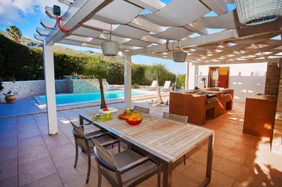 a patio with a table and chairs under a pergola at Villa Pandora in Scopello