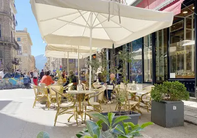 a cafe with tables and chairs and an umbrella at Solemar Sicilia - Design Apartment Palermo in Palermo
