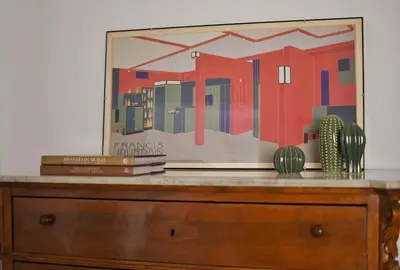 a painting on top of a dresser with books at iFlat Un balcone in Cattedrale in Palermo
