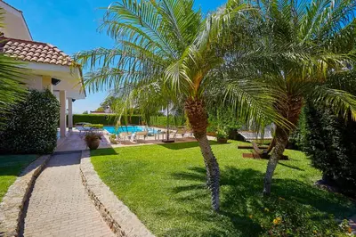 two palm trees in a yard with a swimming pool at Villa Cottone - 5 suite con piscina privata - tra Palermo e Cefalù in Altavilla Milicia